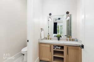Dual vanity with wood-finish cabinetry, light-toned countertop, and gold-finish fixtures