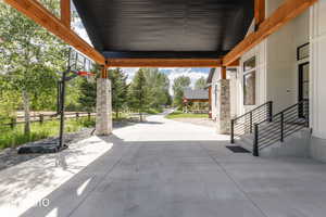 Covered concrete driveway with exposed timber beams and stone-clad columns