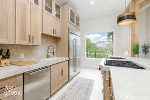 Modern kitchen with light wood cabinetry, stainless steel appliances, a large window showcasing mountain scenery, a built-in gas range, and light-toned countertops