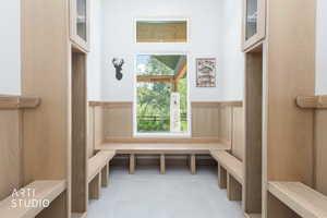 Built-in wood-finish benches and storage cubbies with upper cabinetry frame a large picture window, offering abundant natural light