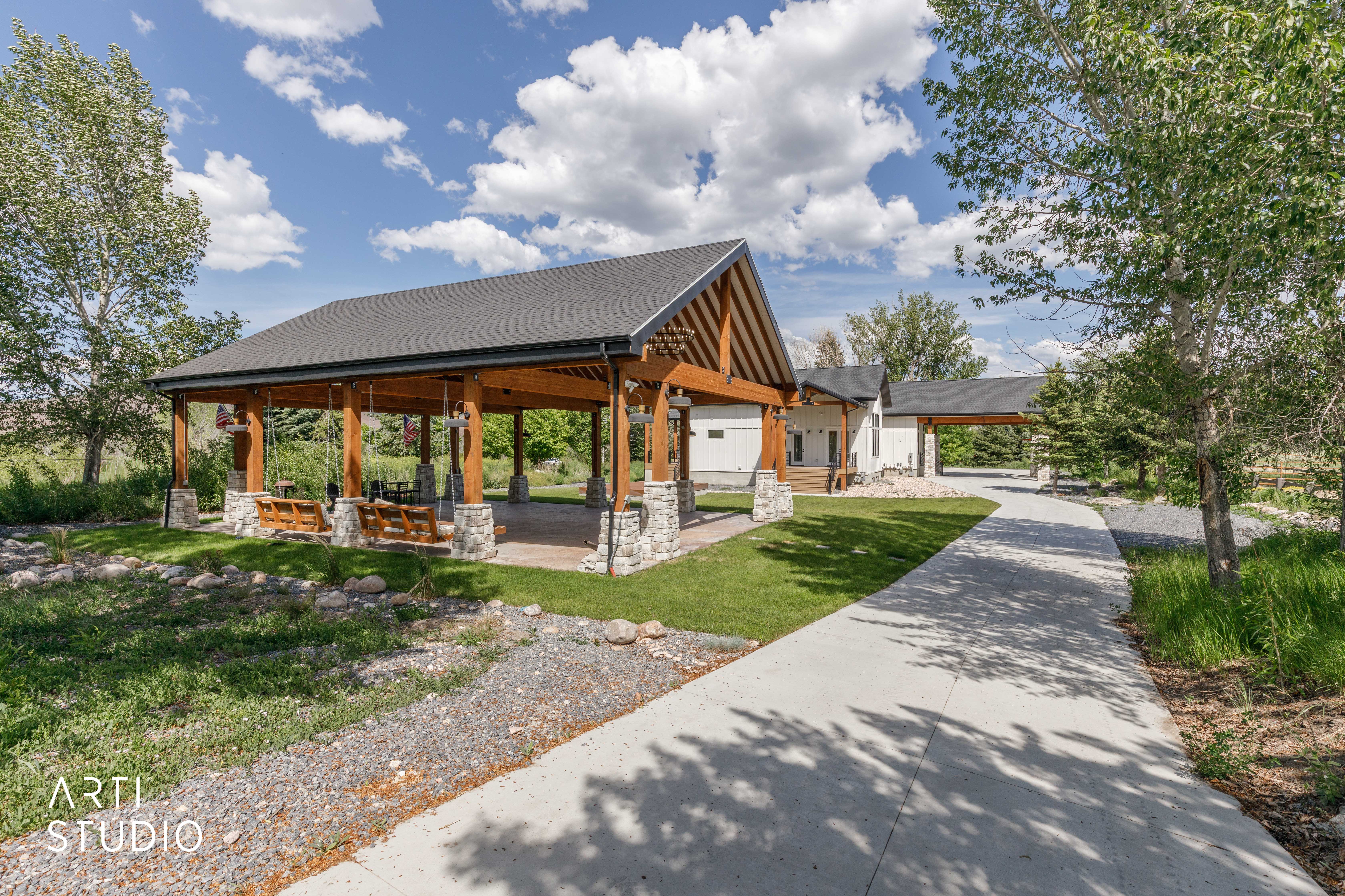 Expansive outdoor pavilion featuring exposed timber framing and stone-clad pillars
