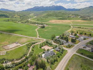 Aerial perspective showcasing expansive green fields, established roads, and distant snow-capped mountains