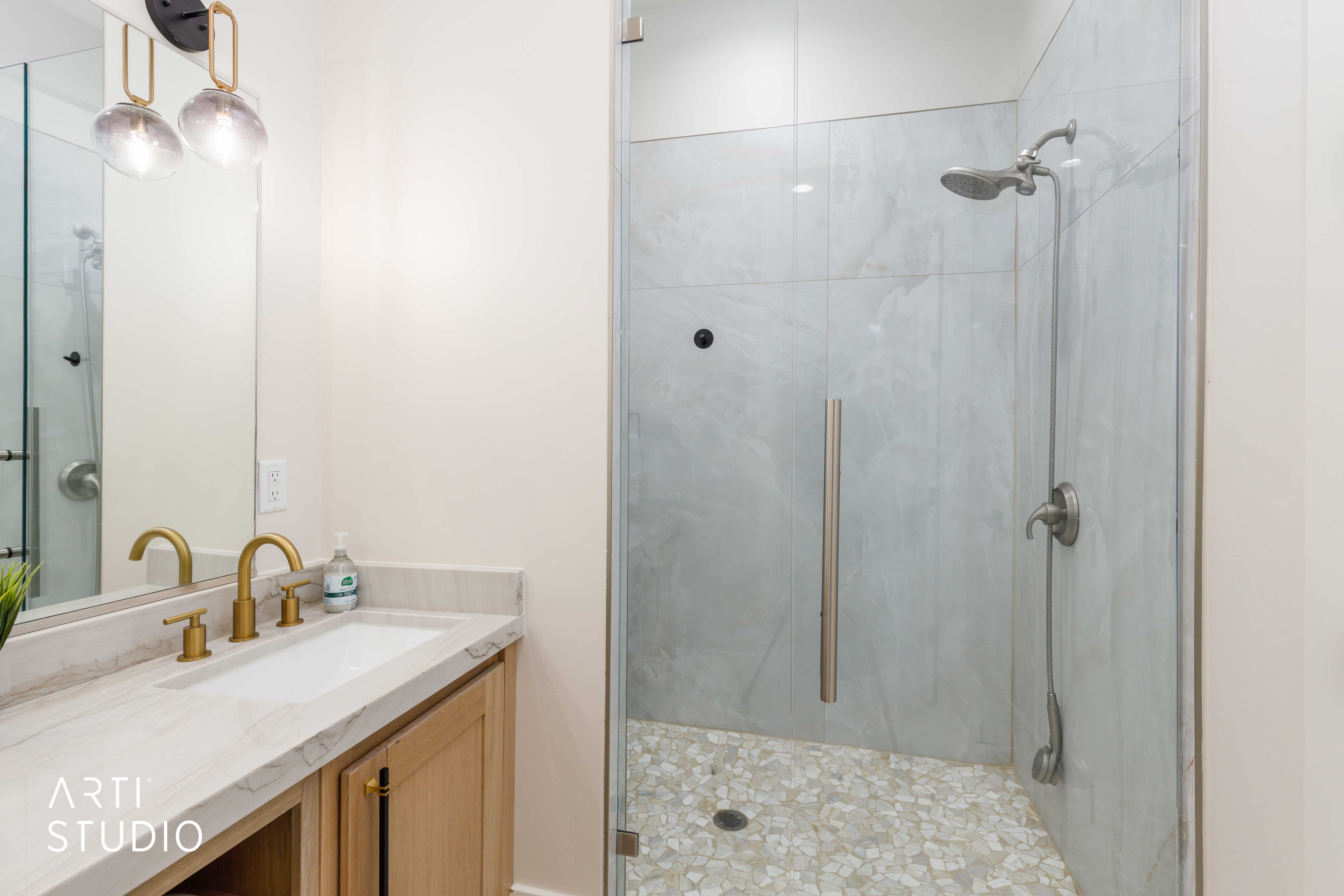 Glass-enclosed shower featuring large format tile surround and pebble tile flooring