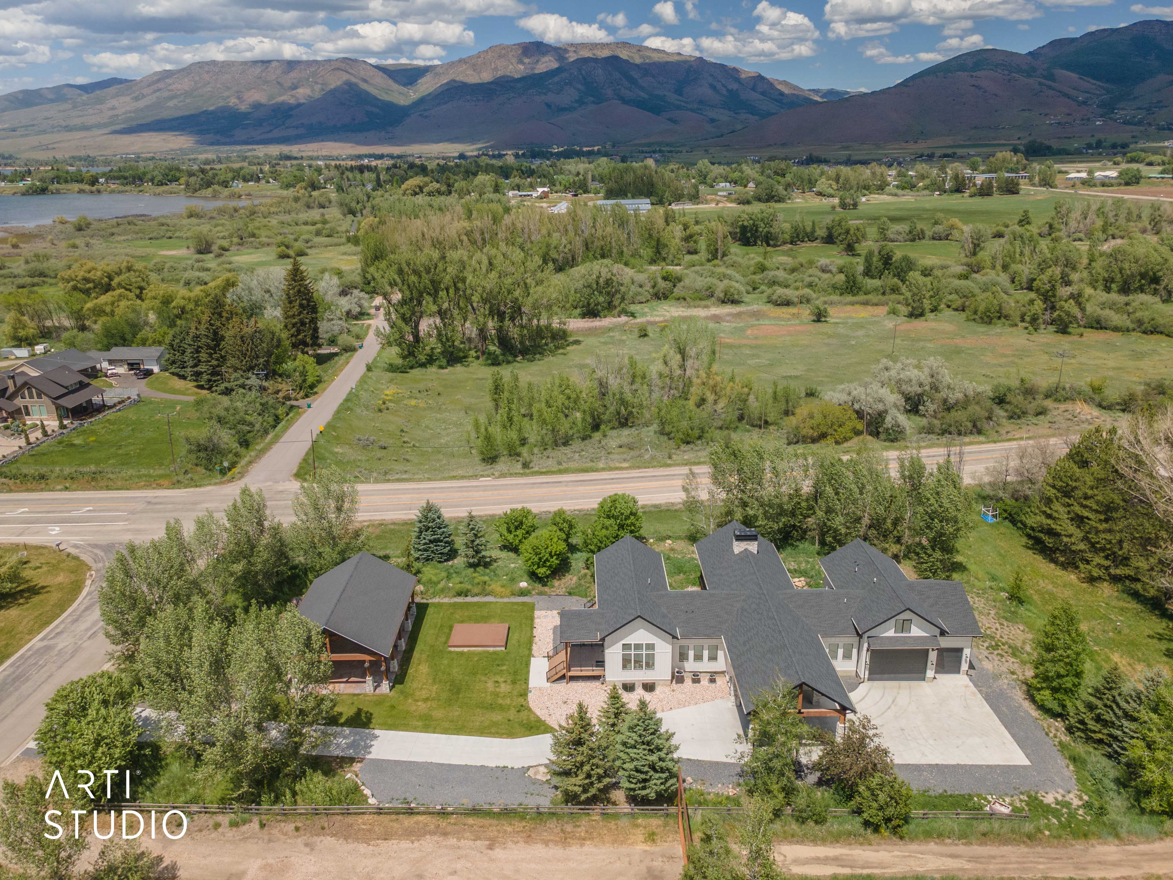 Expansive property featuring a modern residence with a two-car garage, a separate outbuilding, and a large manicured lawn