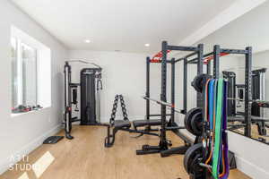 Dedicated fitness space featuring wood-finish flooring, recessed lighting, and a full-wall mirror