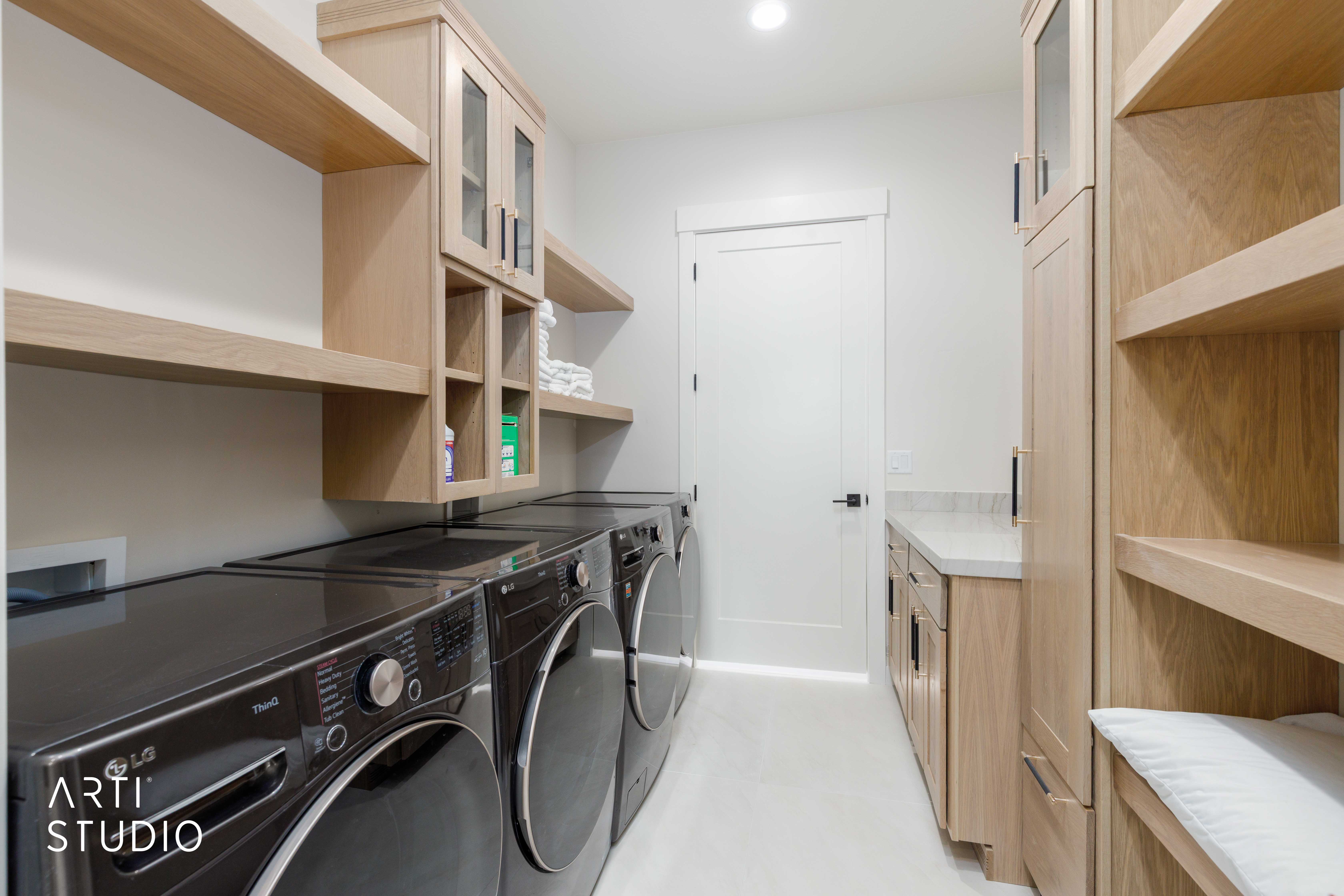 Laundry room featuring light wood-finish cabinetry, open shelving, and a built-in counter