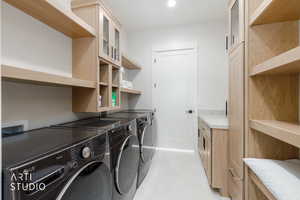 Laundry room featuring light wood-finish cabinetry, open shelving, and a built-in counter
