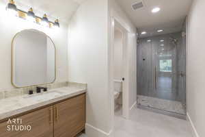 Modern bathroom featuring a wood-finish vanity with gold-tone hardware, a light-toned countertop, and a sleek rectangular undermount sink with a matte black faucet