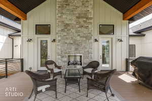 Expansive covered patio featuring a stone fireplace with a built-in firebox, exposed wood beams, and composite decking