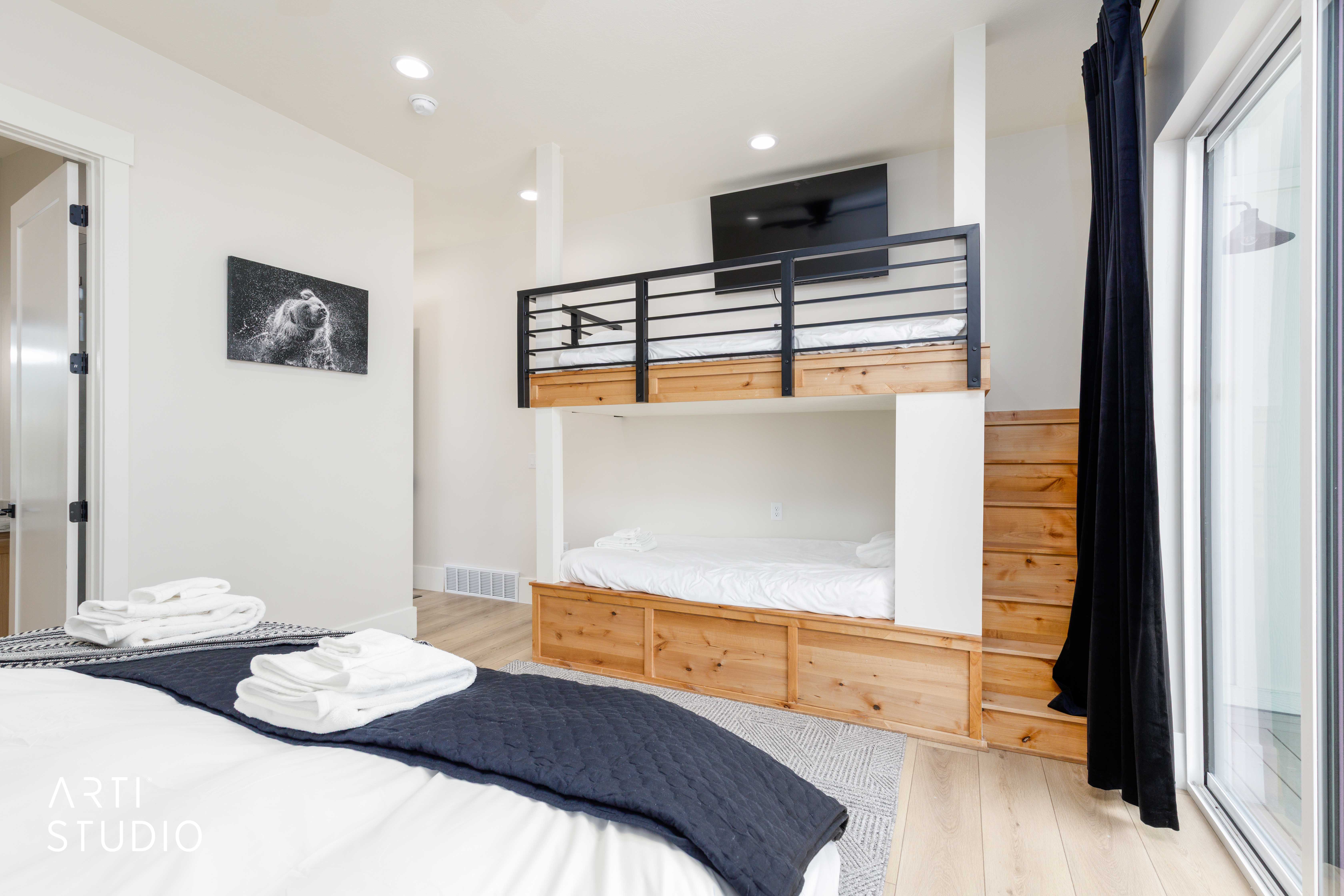 Modern bedroom featuring light wood-finish flooring, recessed lighting, and a built-in bunk bed system with wooden steps