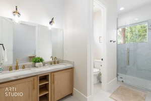 Dual vanity with gold-finish faucets and light wood-finish cabinetry, set against a full-width mirror