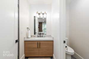 Bathroom featuring a wood-finish vanity with dual doors, a stone countertop, an integrated sink with a matte black faucet, and a rectangular mirror