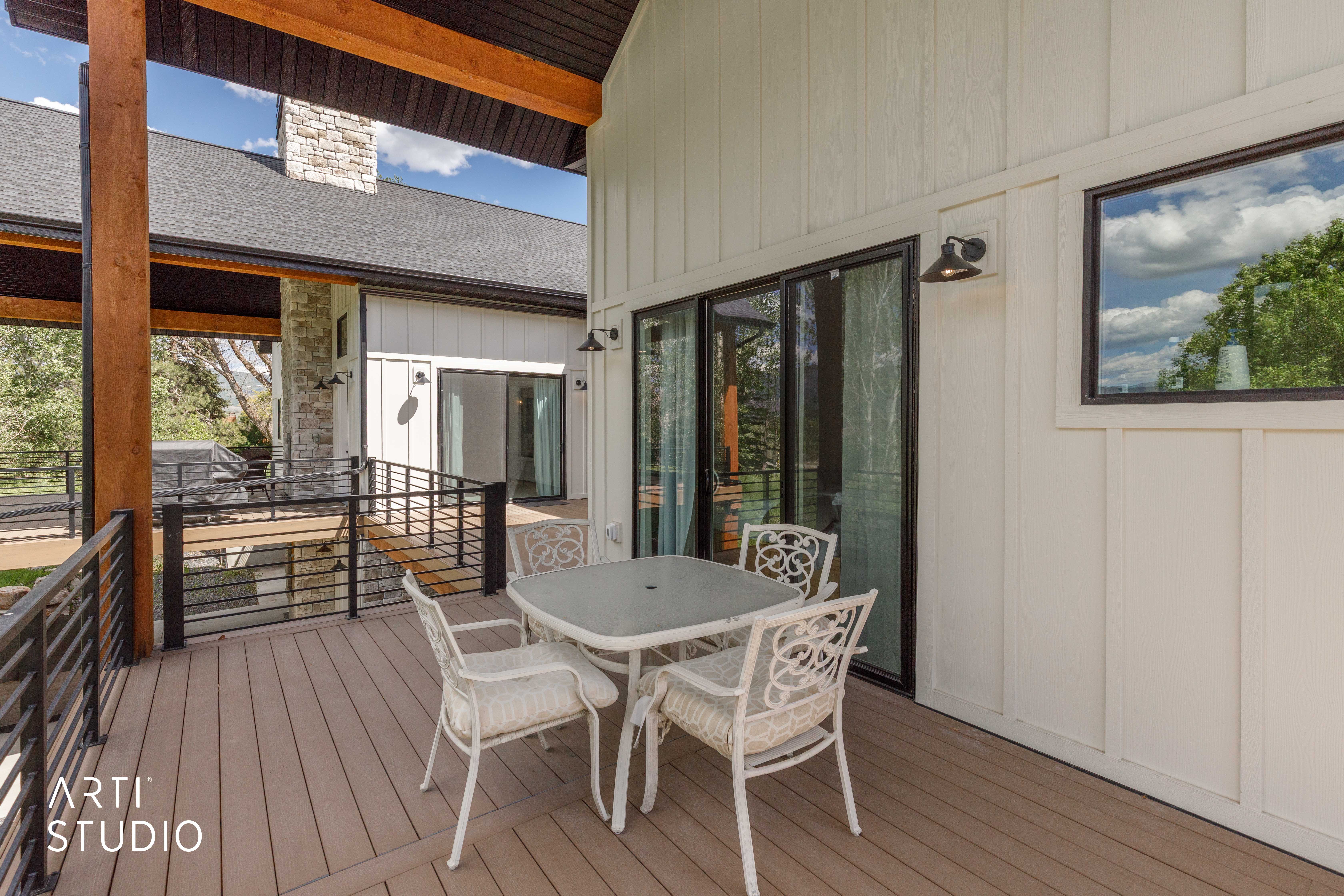Spacious outdoor deck featuring composite decking, black metal railings, and a board and batten exterior