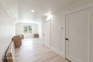 Spacious room featuring light wood-finish flooring, recessed lighting, and a window providing natural illumination