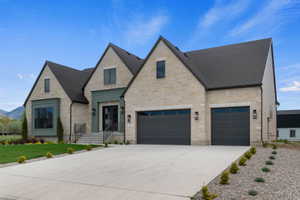 Stone facade residence featuring a two-car garage with dark paneled doors, a striking teal entry surround with double doors, and a prominent bay window