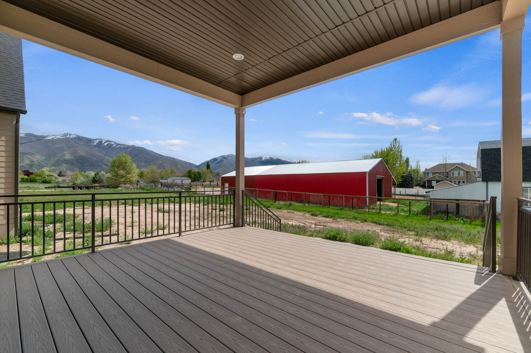 Covered outdoor deck with composite decking and black metal railings