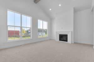Spacious room featuring a vaulted ceiling with exposed beam, multiple large windows, recessed lighting, and a built-in fireplace with a white mantle