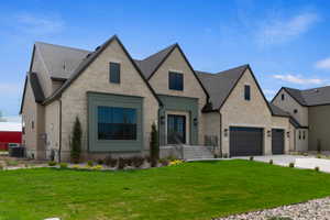 Stone facade property featuring a prominent front entrance with double doors, a two-car garage, and an additional single-car garage