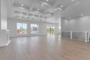 Spacious interior featuring coffered ceilings with recessed lighting, light wood-finish flooring, multiple windows, a built-in fireplace mantle, and a staircase with a railing
