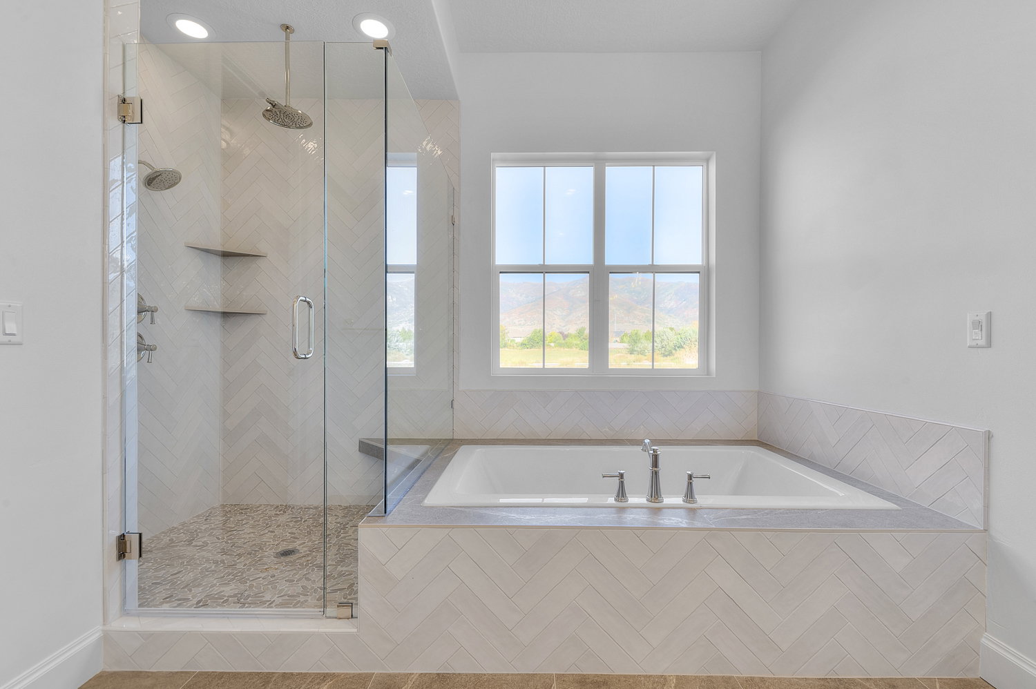 Contemporary bathroom featuring a spacious glass-enclosed shower with pebble-finish flooring and dual showerheads