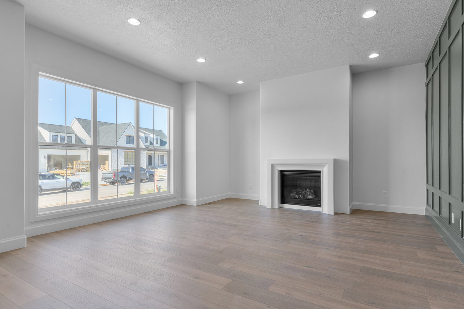 Spacious interior featuring wood-finish flooring, a contemporary fireplace with a white mantel, and a wall of transom windows