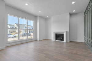 Spacious interior featuring wood-finish flooring, a contemporary fireplace with a white mantel, and a wall of transom windows