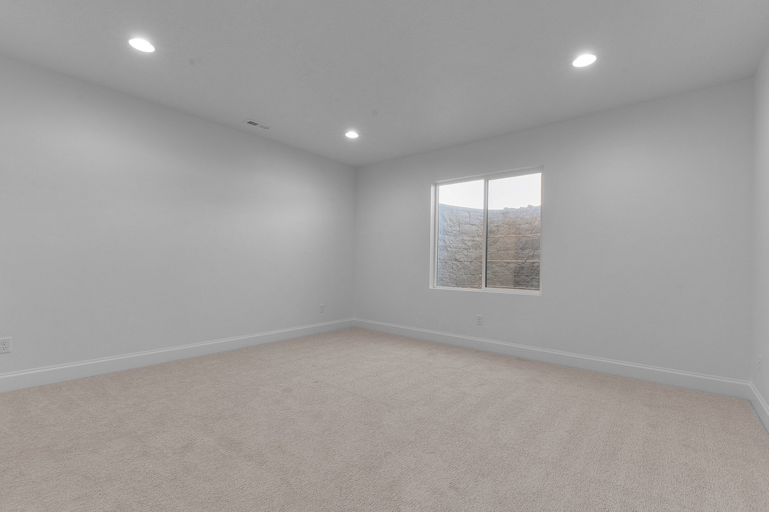Spacious room featuring neutral carpet flooring, recessed lighting, and a window providing natural illumination