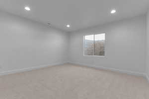 Spacious room featuring neutral carpet flooring, recessed lighting, and a window providing natural illumination