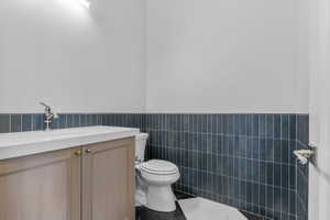 Powder room featuring a light wood-finish vanity with brass hardware, a white countertop, and a polished chrome faucet