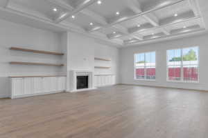 Spacious interior featuring a coffered ceiling with recessed lighting, light wood-finish flooring, and a fireplace with a white surround