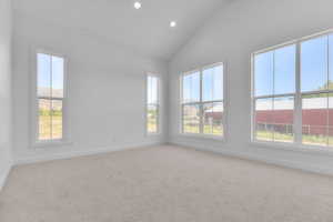 Vaulted ceiling room featuring recessed lighting, multiple large windows with white trim, light-colored carpeting, and white painted walls
