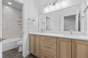 Contemporary bathroom featuring a double vanity with light wood cabinetry, white countertops, and dual undermount sinks