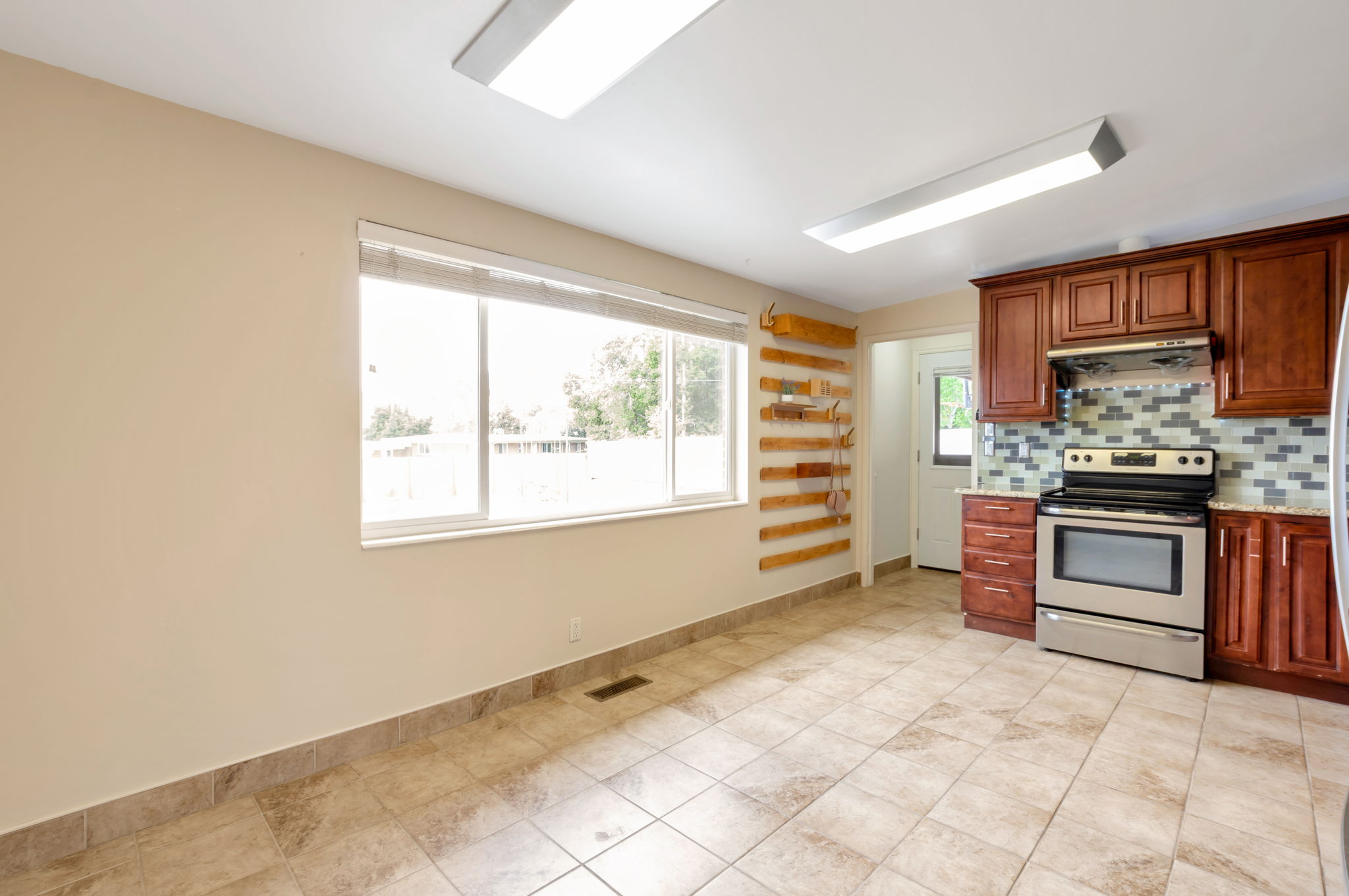 Kitchen featuring wood-finish cabinetry, stainless steel range, and a mosaic tile backsplash