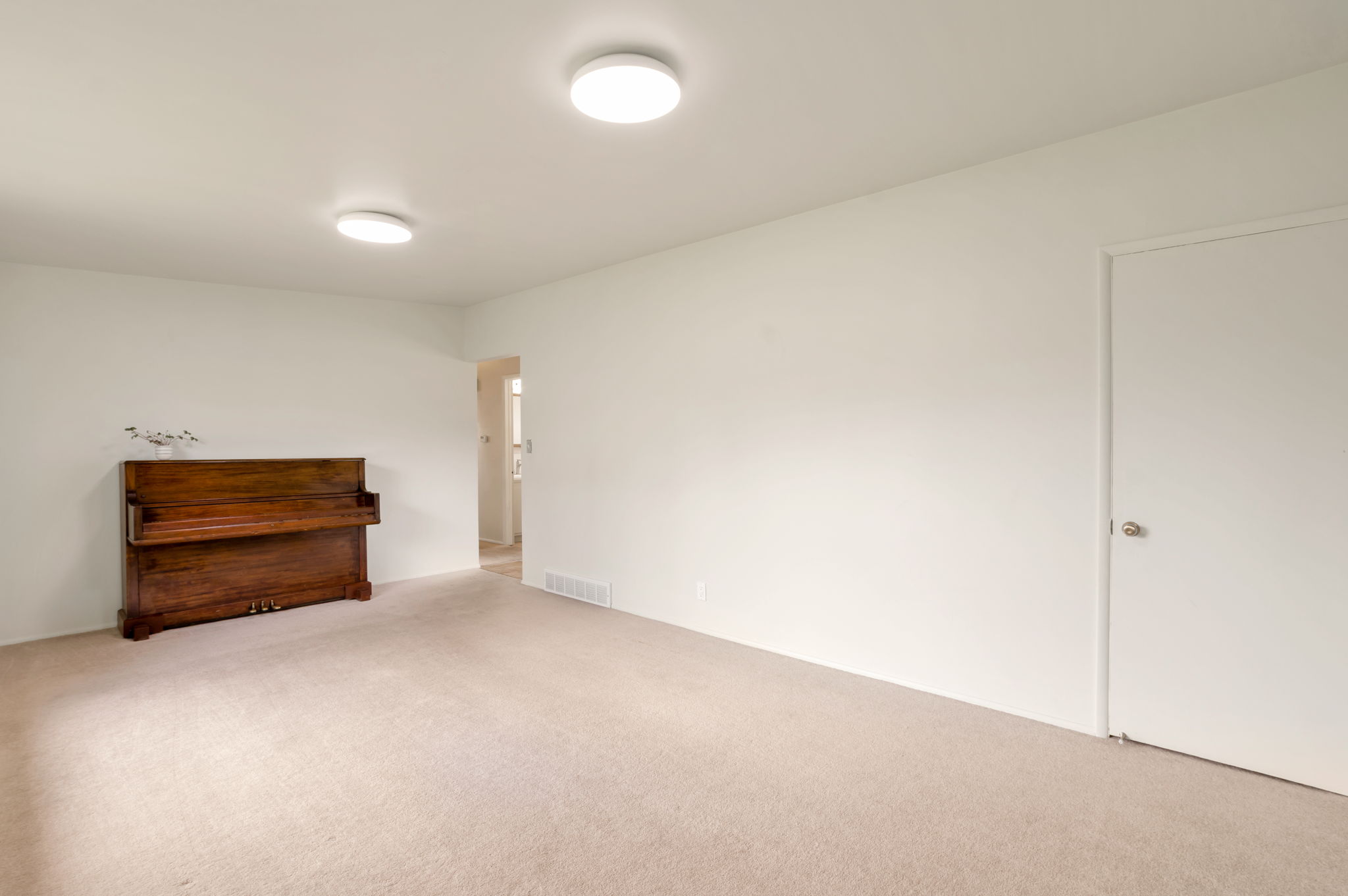 Carpeted interior space featuring white walls and two ceiling-mounted circular light fixtures