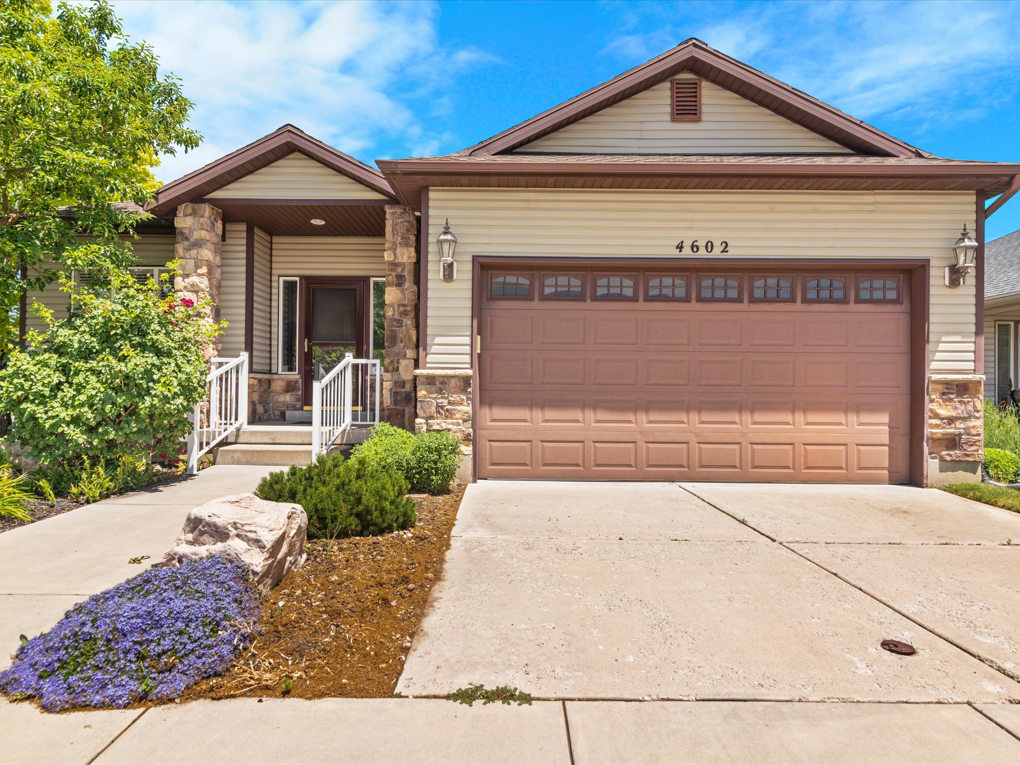 Siding exterior with stone accents, a two-car garage, and a covered entry