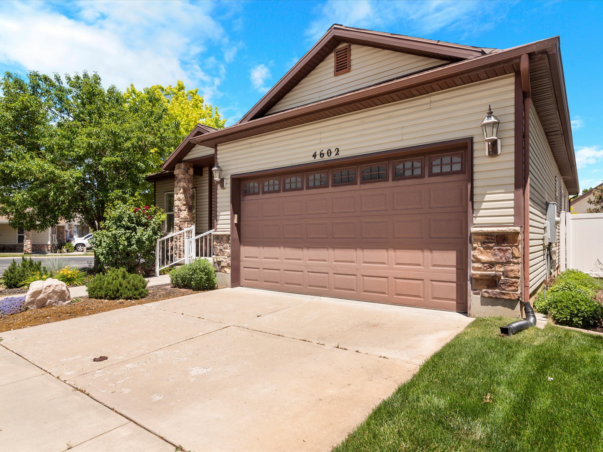 Tan siding exterior featuring a brown garage door with upper window detailing