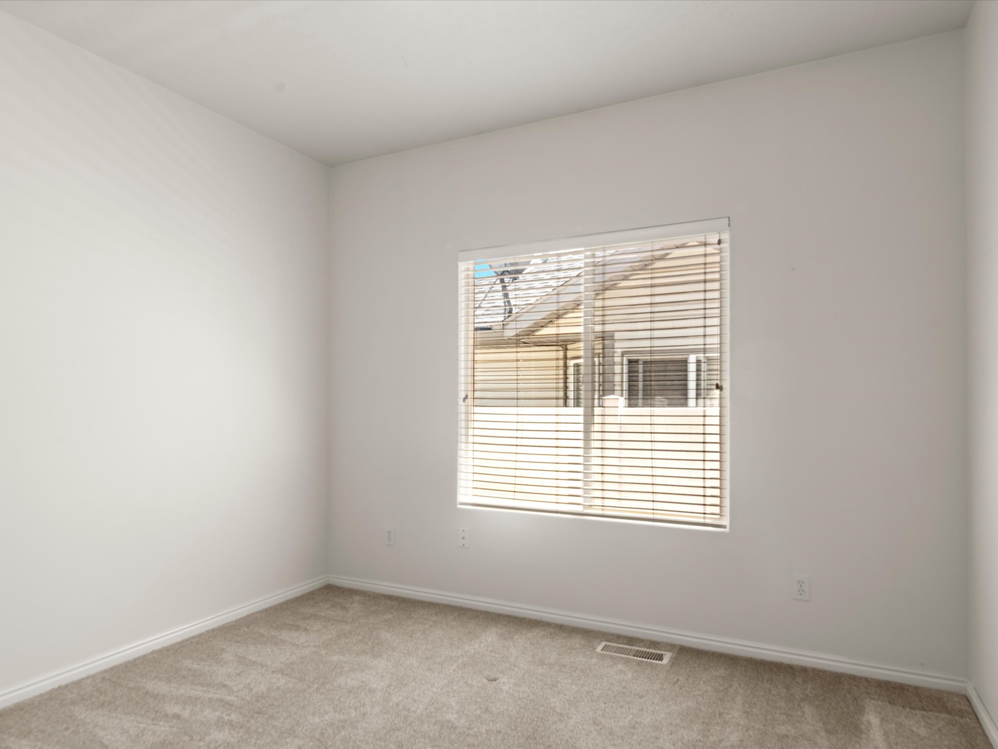 Room featuring a window with horizontal blinds, light-colored carpet, and white baseboards