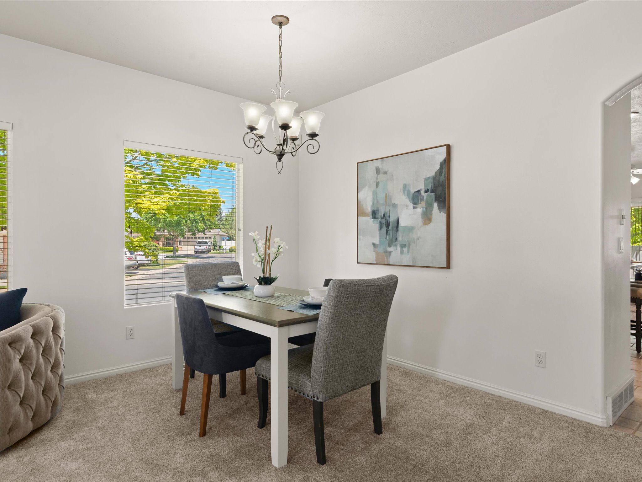 Dining space featuring a multi-bulb chandelier, light neutral-toned carpeting, and white baseboards