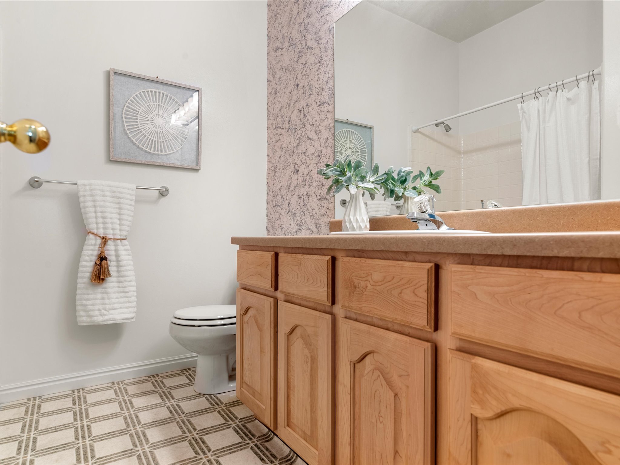 Bathroom featuring a light wood vanity with an integrated sink and an expansive mirror
