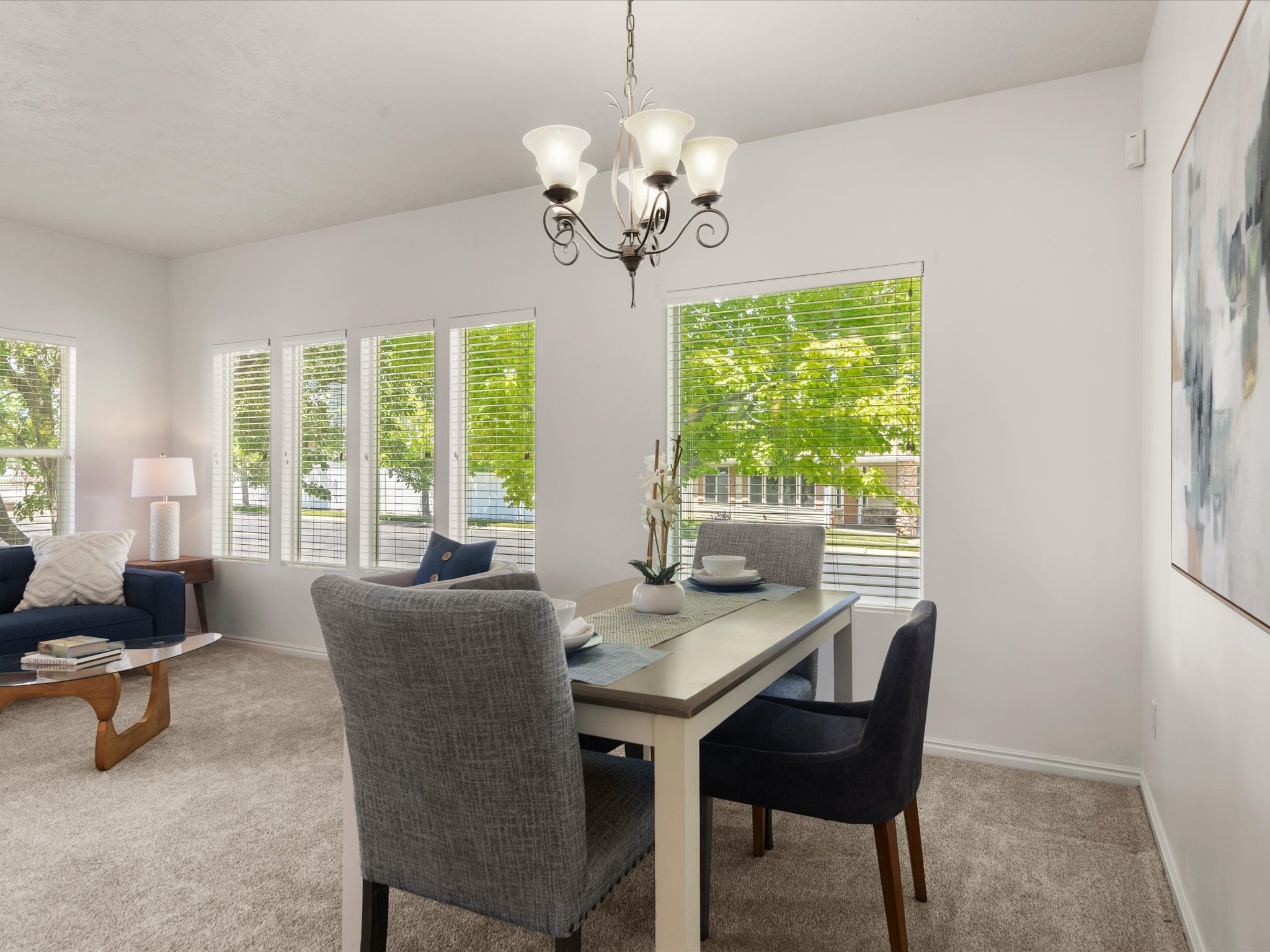 Dining area featuring a classic chandelier and multiple windows with horizontal blinds