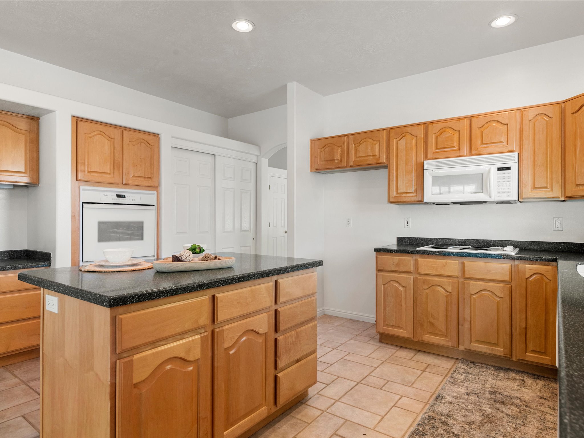 Kitchen featuring natural wood cabinetry, dark speckled countertops, and an integrated wall oven