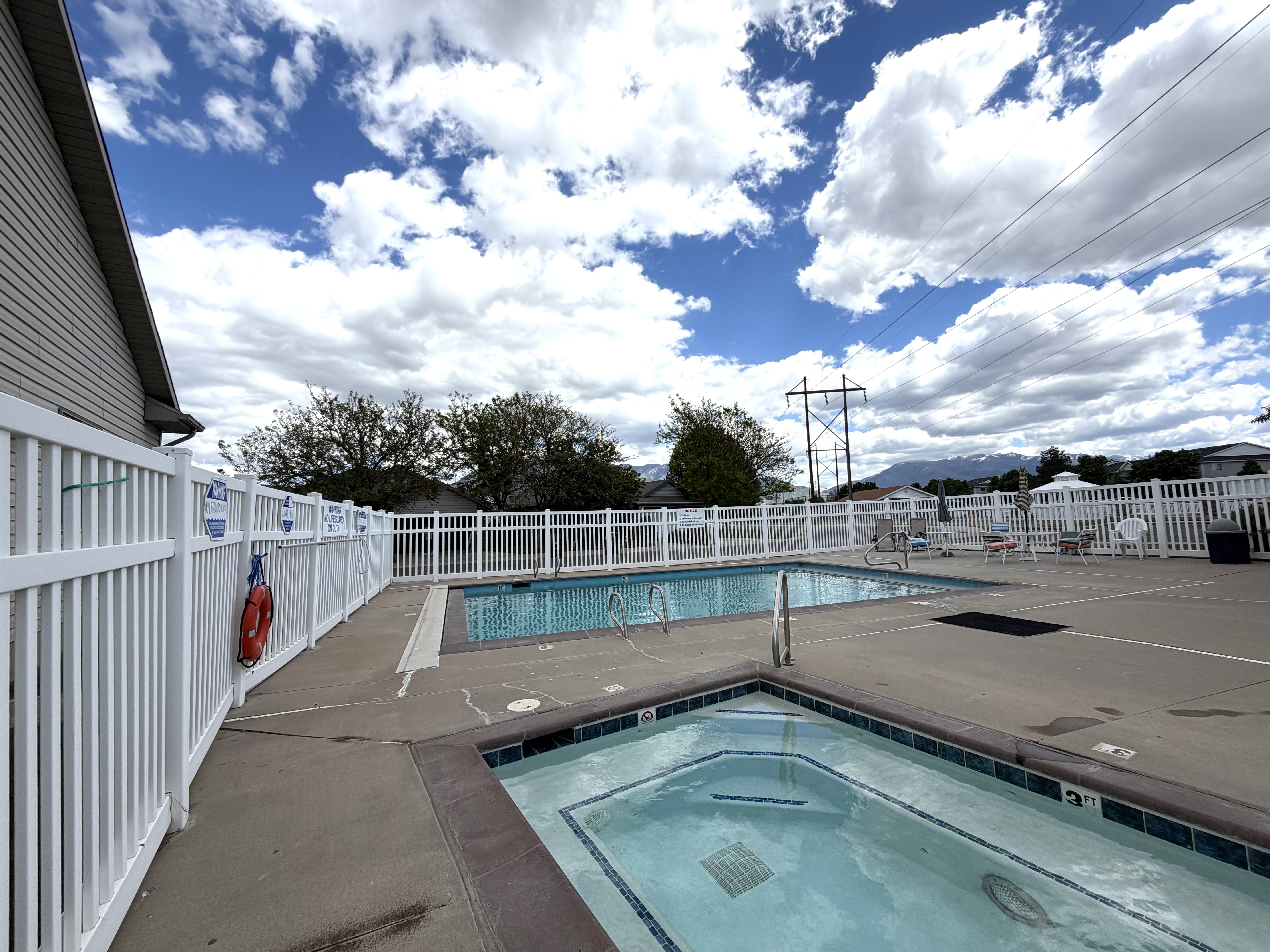 Outdoor aquatic area featuring a swimming pool, separate spa, and surrounding concrete decking