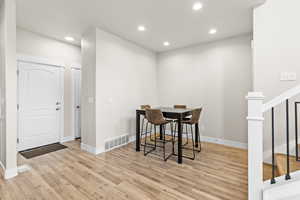 Entry area featuring light wood-finish flooring, recessed lighting, white baseboards, and a white paneled door