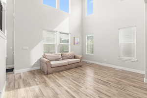 Vaulted ceilings with high windows, wood-finish flooring, white baseboards, and neutral wall tones
