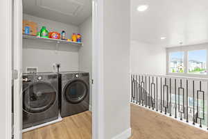 Dedicated laundry closet featuring a built-in shelf, wood-finish flooring, and a white ceiling hatch