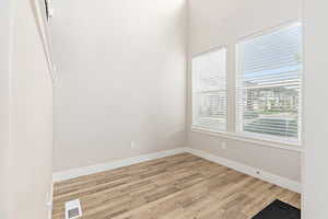 Room featuring two windows with horizontal blinds, wood-finish flooring, and white baseboards