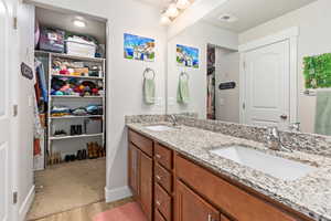 Double vanity featuring integrated sinks, a speckled countertop, and wood-finish cabinetry with silver-tone hardware