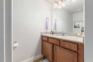 Bathroom vanity featuring a granite countertop with an undermount sink, brushed nickel faucet, and a large mirror