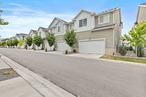 Townhome exterior featuring a two-car garage, light stucco, and horizontal siding