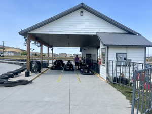 White siding structure with a dark metal roof and an integrated covered concrete pit area